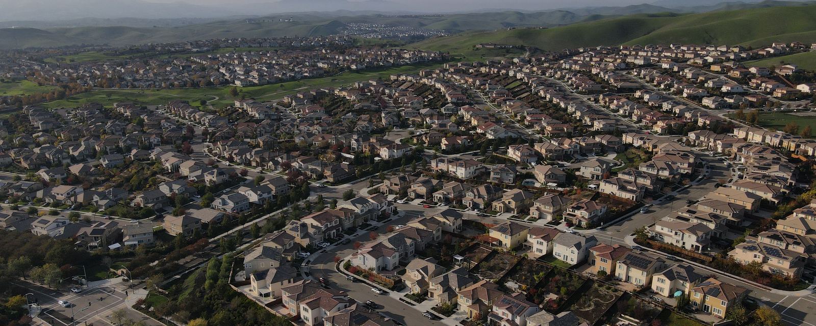 Aerial view of a residential subdivision: rows of two-story homes and backyards along curving streets.